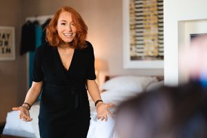 A woman with red hair, wearing a black outfit