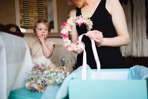 A woman in a black dress holds a floral headpiece