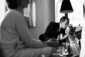 An older man in a suit kisses a smiling young girl