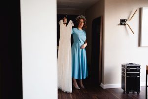 A woman in a blue dress and floral headpiece stands in a room