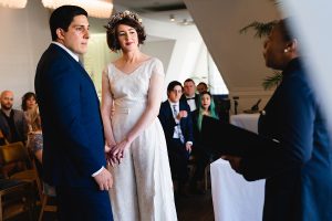 A bride and groom stand holding hands