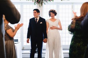 A newlywed couple stands smiling