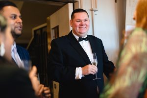 A man in a tuxedo and bow tie smiles