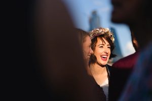 A woman wearing a flower crown laughs joyfully